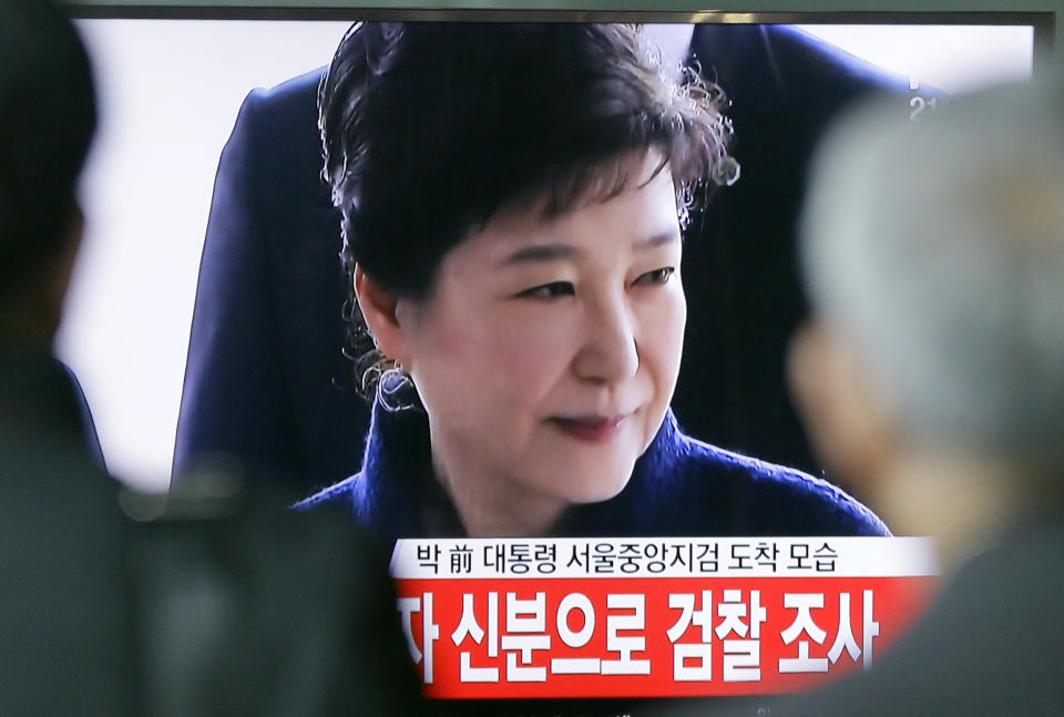 People watch a TV news program showing South Korean ousted President Park Geun-hye's arrival at prosecutors office, at Seoul Railway Station in Seoul, South Korea, Tuesday, March 21, 2017. Park said Tuesday she was "sorry" to the people as she underwent questioning by prosecutors over a corruption scandal that led to her removal from office. The letters read " Park Geun-hye arrives at prosecutors office." (AP Photo/Ahn Young-joon)
