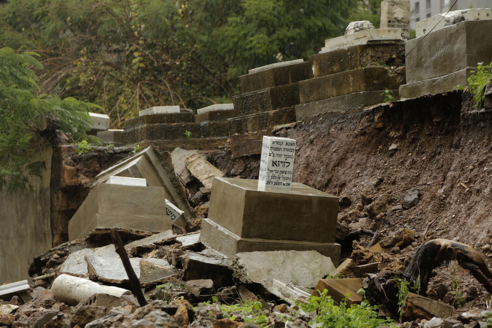 CORRECTS TO CAPITAL'S ONLY JEWISH CEMETERY, NOT COUNTRY'S - Graves from a Jewish cemetery lie on a sidewalk after it collapsed following heavy rains in the Sodeco area of Beirut, Lebanon, Thursday, Dec. 26, 2019. A heavy storm hit Lebanon with heavy rain and strong winds causing an old wall to collapse in the capital's only Jewish cemetery, causing damage to several tombstones. Lebanon once had a thriving Jewish community, but the various Arab-Israeli wars and Lebanon's own 1975-90 civil war caused waves of emigration and almost none are left in the country today. (AP Photo/Hassan Ammar)