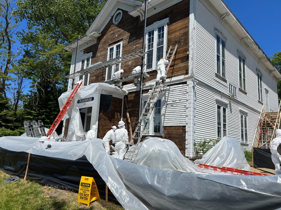 Workers on ladders and scaffolding remove shingles from the historic Academy Playhouse, home of the Academy of Performing Arts in Orleans.