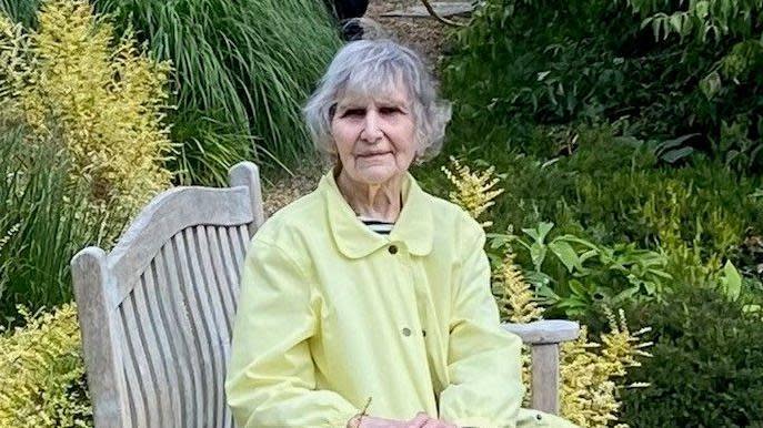 Olga Henderson sitting on a bench in a garden