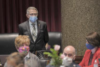 In this May 11, 2020, photo provided by the Missouri House, Rep. Joe Runions wears a protective mask while standing near his desk in the House chamber in Jefferson City, Mo. Runions, a Democrat from the Kansas City suburb of Grandview who had been out for six weeks with COVID-19, was upset that many Republican lawmakers did not wear masks as a precaution against spreading the virus. (Tim Bommel/Missouri House via AP)