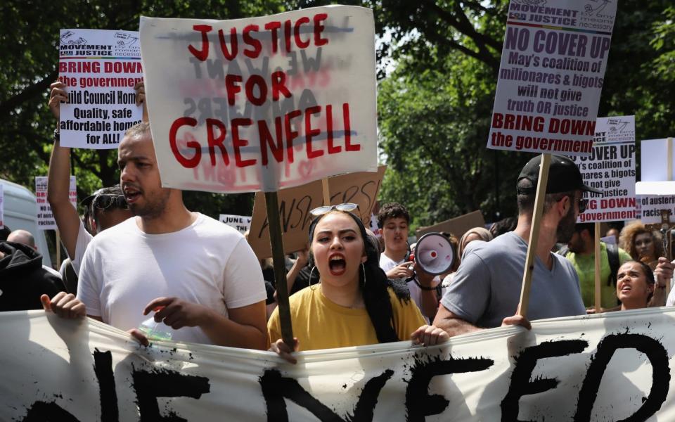 Protesters hold signs calling for justice for the victims of the Grenfell Disaster - Credit: Dan Kitwood/Getty