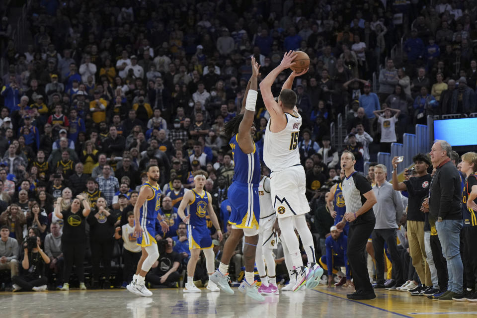 Denver Nuggets center Nikola Jokic (15) hits a 3-pointer over Golden State Warriors forward Kevon Looney to give the Nuggets the win in an NBA basketball game Thursday, Jan. 4, 2024, in San Francisco. (AP Photo/Loren Elliott)