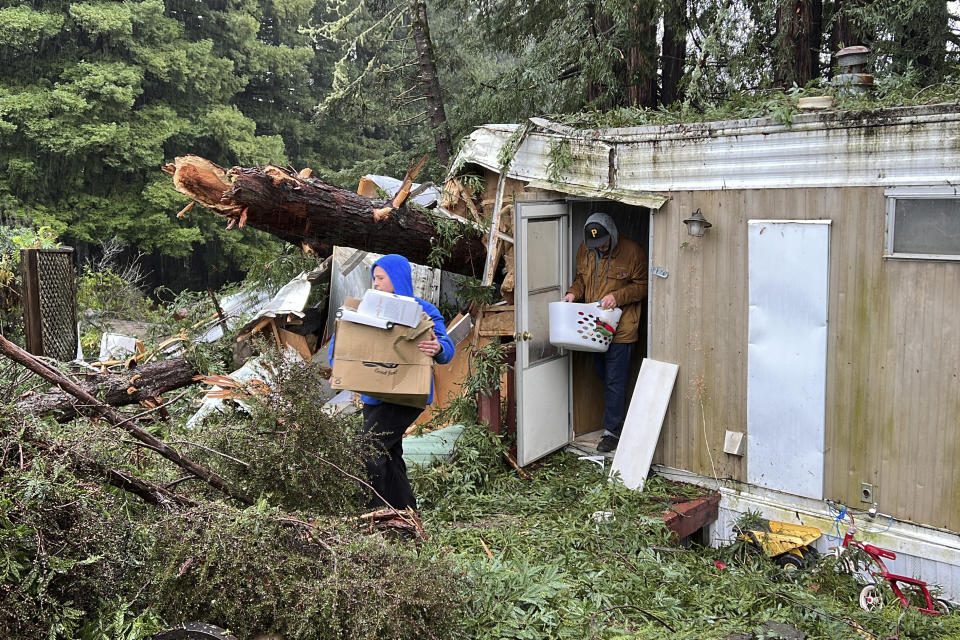 Family friends remove items from the mobile home where 2-year-old Aeon Tocchini was killed by a fallen redwood tree in Occidental, Calif., Thursday, Jan. 5, 2023. Damaging hurricane-force winds, surging surf and heavy rains from a powerful "atmospheric river" pounded California on Thursday, knocking out power to tens of thousands, causing flooding, and contributing to the deaths of at least two people. (AP Photo/Terry Chea)