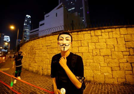 Anti-government protesters, including one in a Guy Fawkes mask, mill around outside the People's Liberation Army Hong Kong garrison headquarters in Hong Kong's Admiralty district