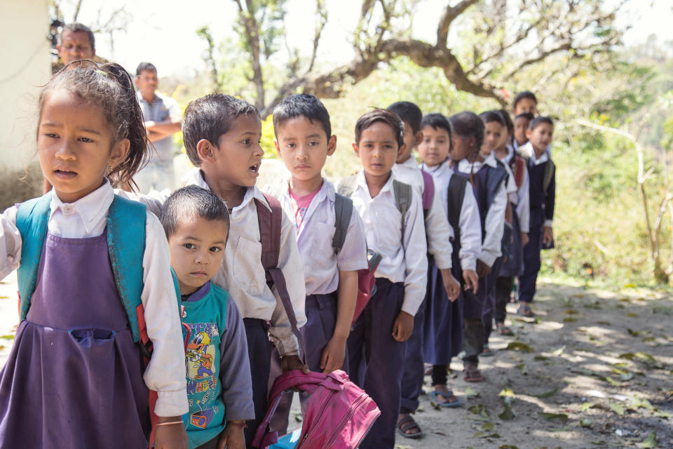 Village elementary school kids forming line for morning prayer. different age group children wearing school uniform.