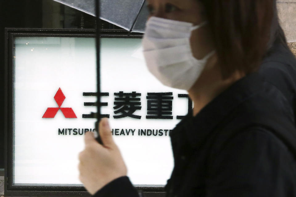 A woman walks past the company sign of the Mitsubishi Heavy Industries in Tokyo Tuesday, July 16, 2019. Colonial-era Korean laborers are seeking a court approval for the sales of local assets of their former Japanese company as it is refusing to compensate them. Lawyers for Koreans who worked for the Japanese company say they’ll soon request a South Korean court to authorize the sales of some of Mitsubishi’s seized assets in South Korea. (AP Photo/Koji Sasahara)