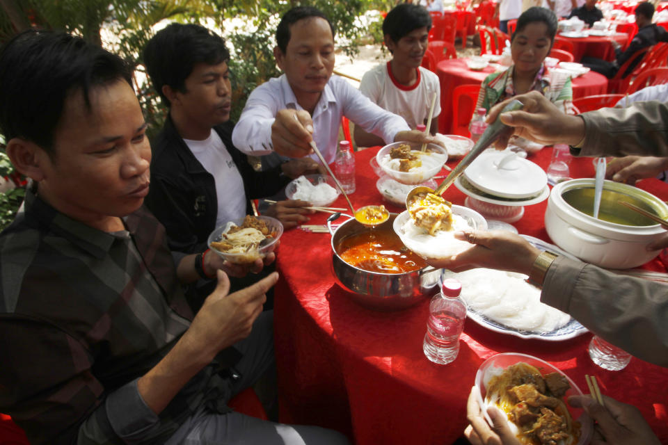 Cambodian garment workers eat noodle at a Buddhist pagoda at outside Phnom Penh, Cambodia, Sunday, June 9, 2019. The bitter decadeslong rivalry between Hun Sen, Cambodia's strongman leader, and Sam Rainsy, the self-exiled chief political rival and critic, has sometimes played out in deadly violence. But on Sunday, soup rather than blood was likely to be spilled. (AP Photo/Heng Sinith)