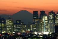Japan's highest mountain Mount Fuji (top C) is seen behind the skyline of the Shinjuku area of Tokyo at sunset on November 27, 2014