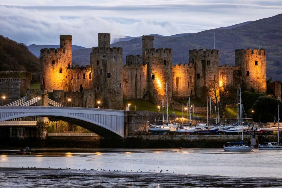Photograph taken at night facing towards the illuminated Conwy Castle from the east bank of the River Conwy on 30th November 2021.