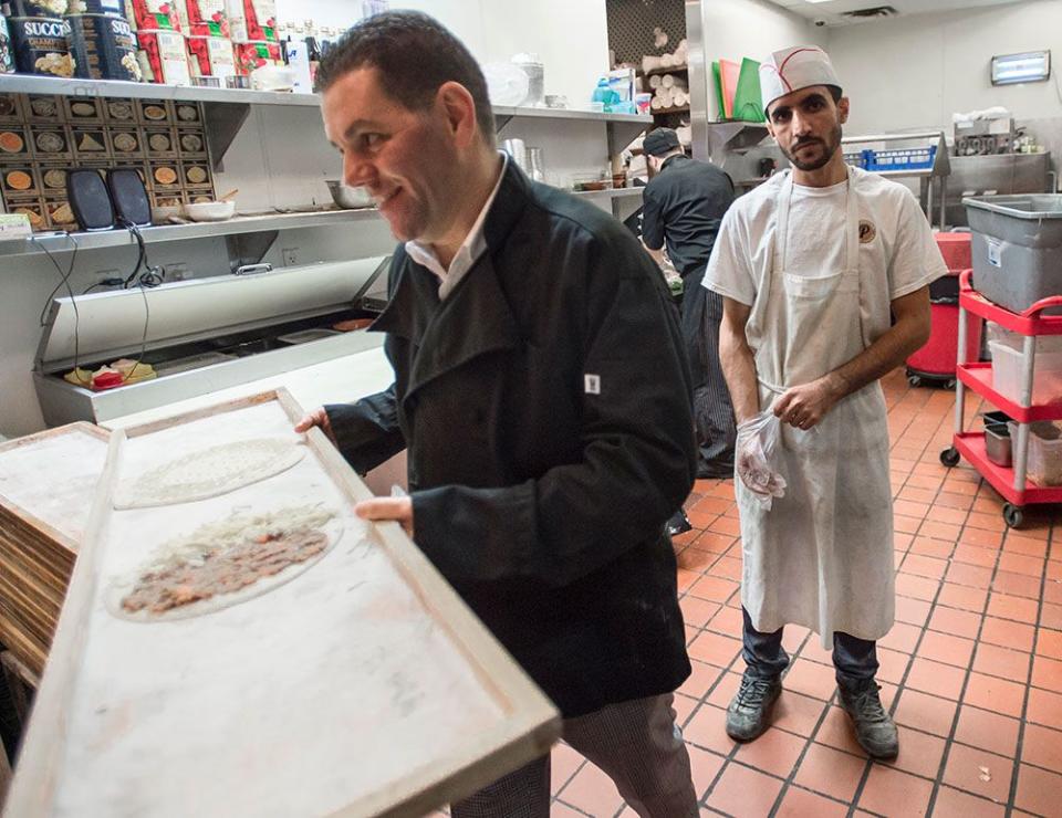  Mohamad Fakih, left, works with a Syrian refugee at one of his restaurants in Mississauga, Ontario, in 2016.