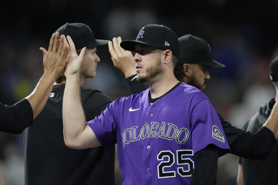 Colorado Rockies first baseman C.J. Cron is congratulated by teammates after the ninth inning of a baseball game against the Texas Rangers Tuesday, Aug. 23, 2022, in Denver. (AP Photo/David Zalubowski)