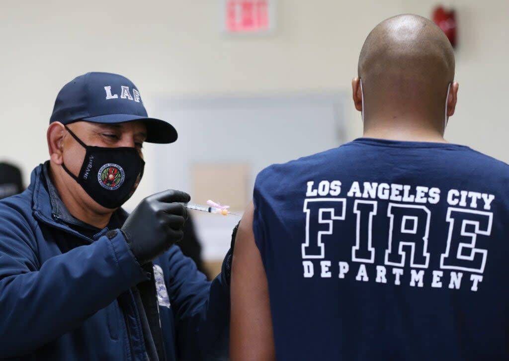 A Los Angeles Fire Department (LAFD) firefighter receives a Moderna COVID-19 vaccination dose from firefighter Michael Perez (L) at a fire station on January 29, 2021 in Los Angeles, California. LAFD has recorded a ‘sharp decline’ in coronavirus cases after firefighters began receiving the vaccine shots on December 28. (Photo by Mario Tama/Getty Images)