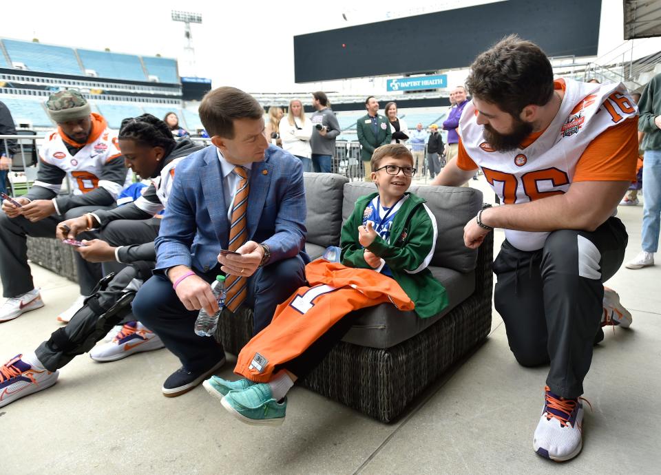 Blake Hunter, 10 who is a participant in the TaxSlayer Gator Bowl's "Dream Team," chats with Clemson coach Dabo Swinney and offensive lineman John Williams after Thursday's team press conference at EverBank Stadium.