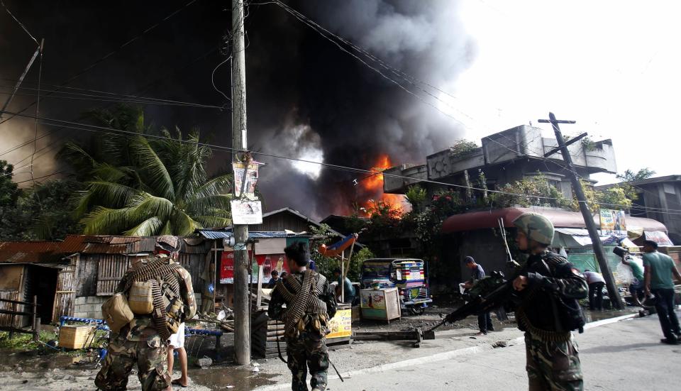 Government soldiers secure a street as fire spreads in a residential neighbourhood after a firefight with Muslim rebels from the Moro National Liberation Front (MNLF) in Zamboanga city, in southern Philippines, September 12, 2013. Fighting between security forces and the rogue Muslim rebels seeking to declare an independent state escalated in Zamboanga city on Thursday and spread to a second island, officials said. U.S.-trained commandos exchanged gunfire with a breakaway faction of the MNLF holding dozens of hostages in Zamboanga City, on the southernmost island of Mindanao, army spokesman Domingo Tutaan said. REUTERS/Erik De Castro (PHILIPPINES - Tags: CIVIL UNREST CONFLICT POLITICS)