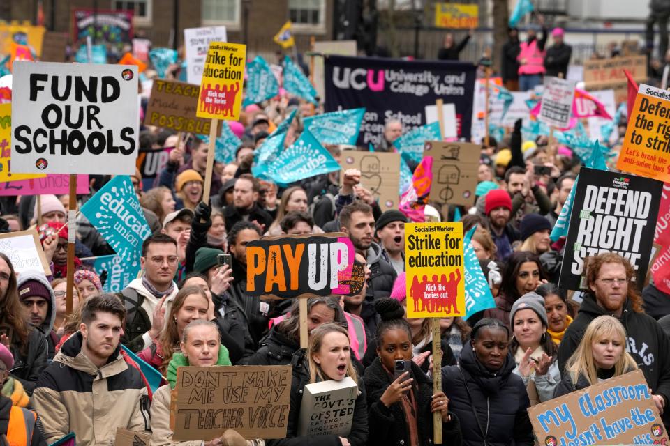 Thousands of demonstrators wave banners as they stand near Downing Street in Westminster in London, Wednesday, Feb. 1, 2023.