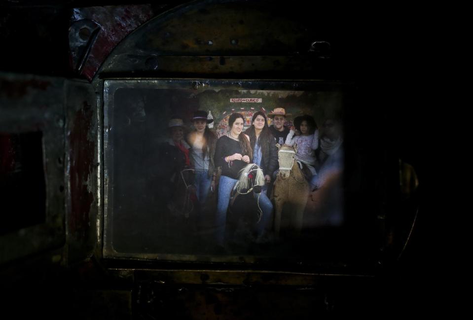 En esta imagen del 4 de septiembre de 2016, una familia posando para ser retratada vista a través de la vieja cámara de cajón de Luis Maldonado, en una feria que celebra el Día de Independencia de Chile en Santiago de Chile. El mecanismo de la cámara es sencillo: la luz entra a través de una lente y el papel fotográfico que hay dentro captura un negativo del objeto fotografiado. (AP Foto/Esteban Félix)