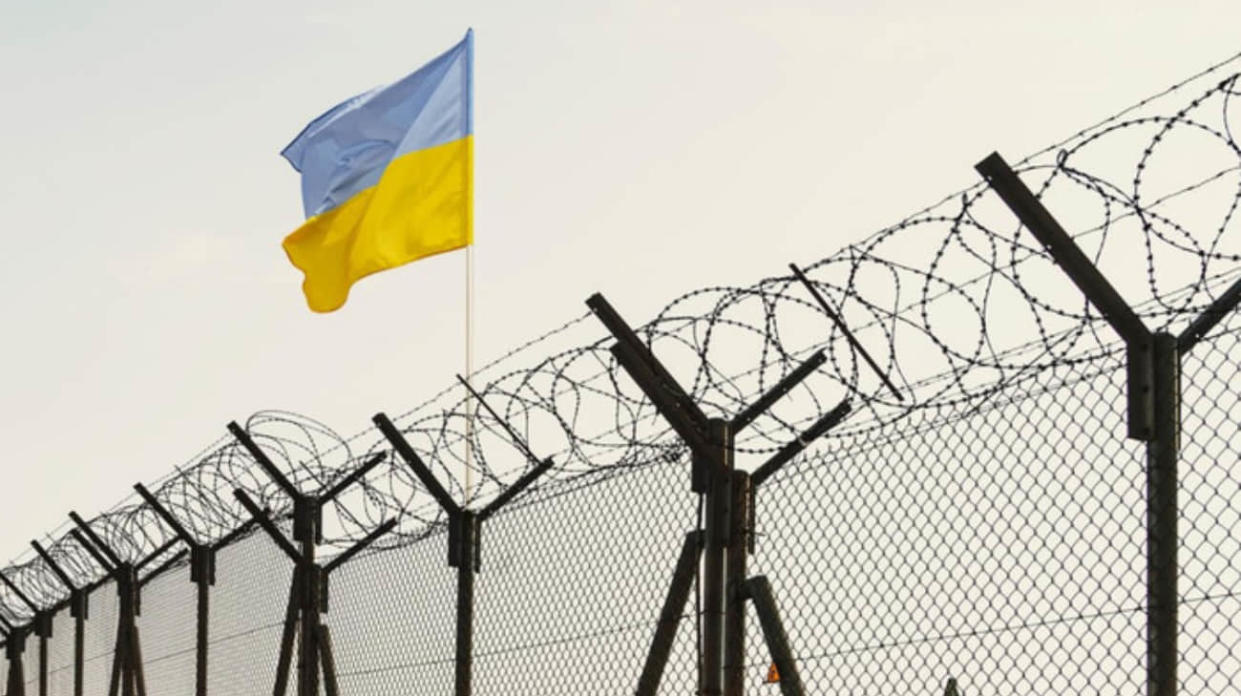 Ukrainian flag over barbed wire. Stock photo