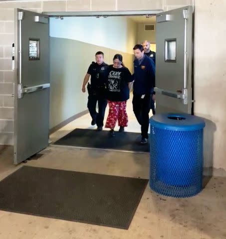 <p>San Antonio Police Department</p> Myrta Romanos is escorted out of the police precinct Wednesday afternoon, charged with three felonies connected to the capital murders of a young pregnant couple.