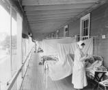 Masked Nurse at the Head of a Row of Beds Treating Patient during Influenza Pandemic, Walter Reed Hospital, Washington DC, USA, Harris & Ewing, 1918. (Photo by: Universal History Archive/Universal Images Group via Getty Images)