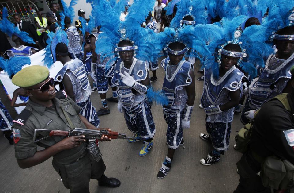 A policeman stand guards as performers prepare to walk through the street during Lagos Carnival in Lagos, Nigeria, Monday, April. 1, 2013. Performers filled the streets of Lagos' islands Monday as part of the Lagos Carnival, a major festival in Nigeria's largest city during Easter weekend. (AP Photo/Sunday Alamba)