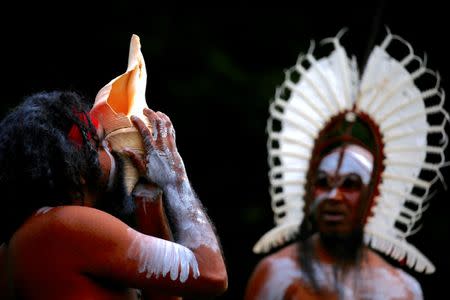 An Australian Aboriginal man blows into a shell as an indigenous man from the Torres Strait Islands wearing traditional dress performs during a welcoming ceremony at Government House in Sydney, Australia, June 28, 2017. REUTERS/David Gray