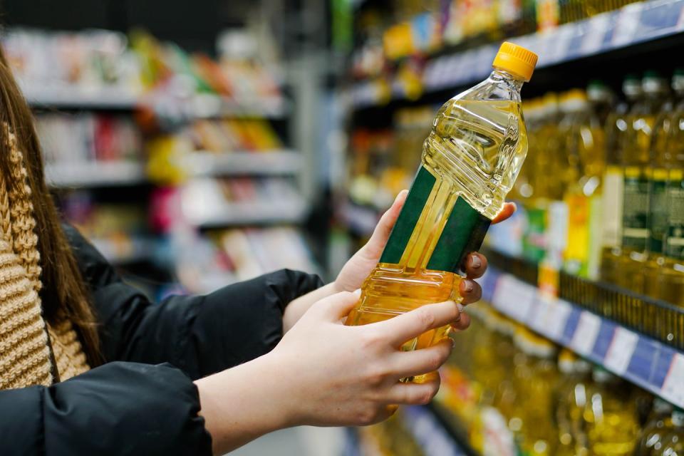 woman choosing sunflower oil in the supermarket close up of hand holding bottle of oil at store