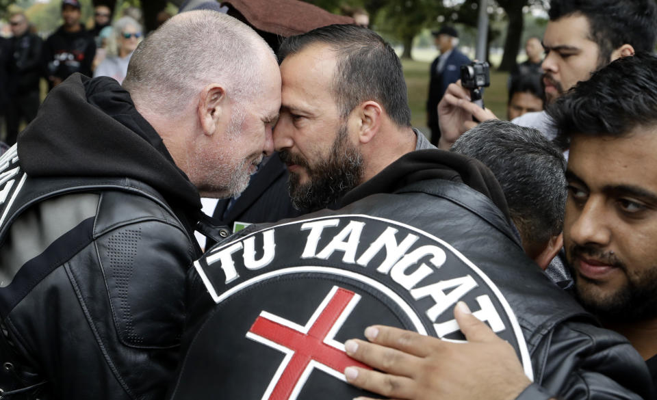 Survivor of the Al Noor mosque shootings, Temel Atacocugu, center, exchanges a hongi with a member of the Tu Tangata motorcycle club outside the mosque in Christchurch, New Zealand, Sunday, March 15, 2020. A national memorial in New Zealand to commemorate the 51 people who were killed when a gunman attacked two mosques one year ago has been canceled due to fears over the new coronavirus. (AP Photo/Mark Baker)