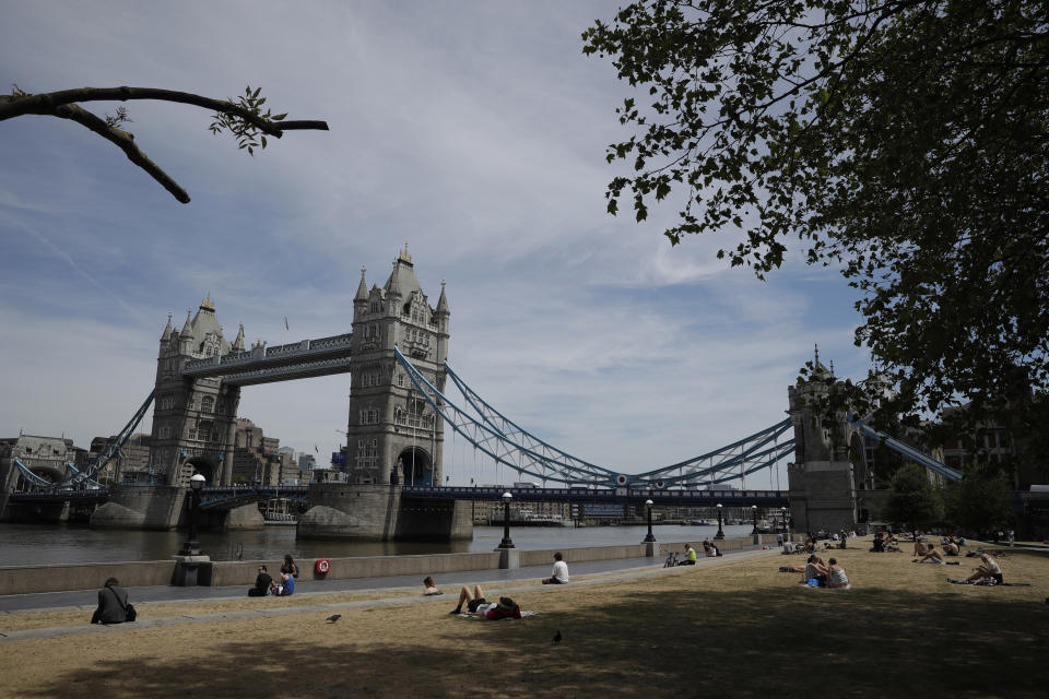 FTSE: People relax in the sun backdropped by Tower Bridge