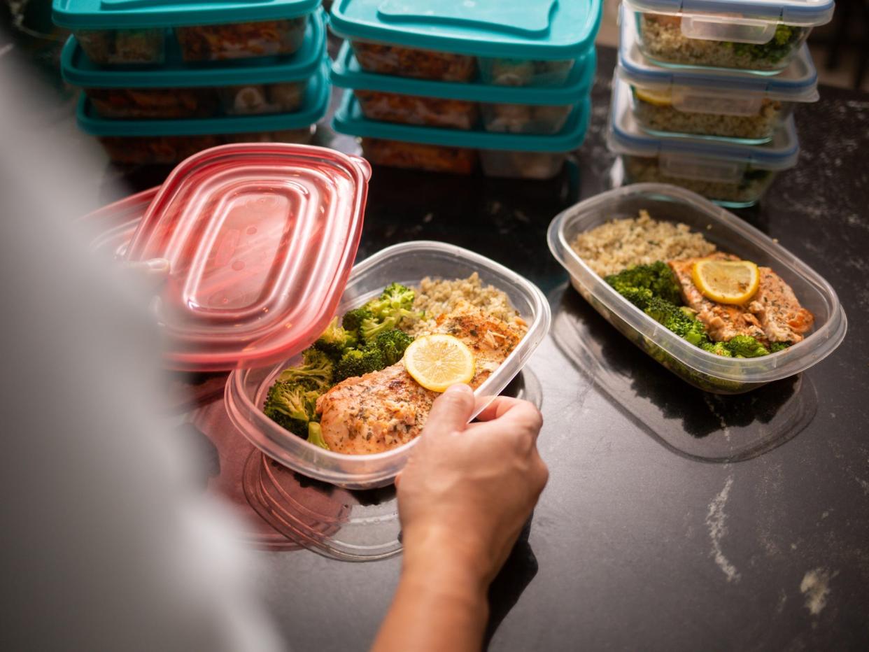 a closeup of a stack of meal prepped dinners of salmon, veggies, and rice in food storage containers.