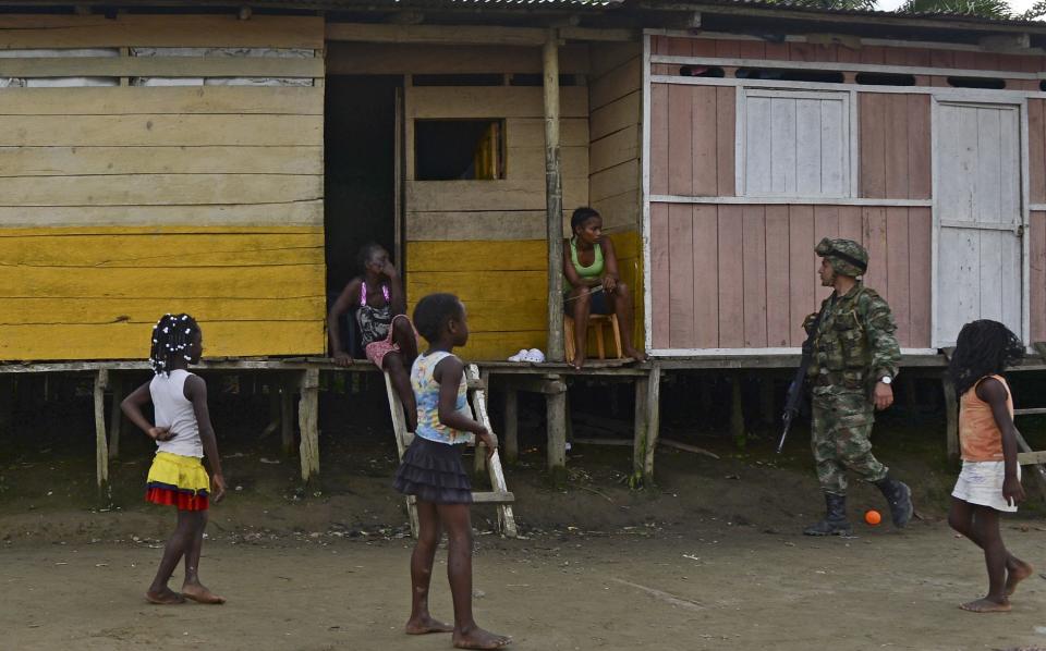 A soldier patrols the streets near children in Las Mercedes, rural area of Quibdo, Department of Choco, Colombia