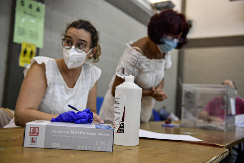 Polling station staff wear face masks to help curb the spread of the coronavirus during the Basque regional election in the village of Durango, northern Spain, Sunday, July 12, 2020. Basque authorities display special rules and practices in the protection against the coronavirus. (AP Photo/Alvaro Barrientos)