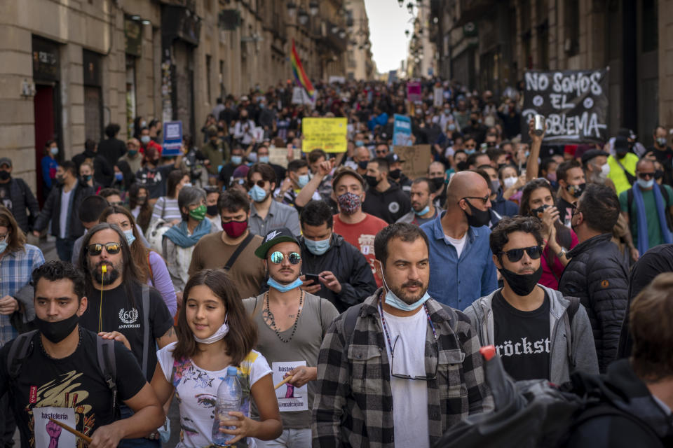 Workers of several sectors including restaurants, bars, hotel, taxi, and nightclubs march during a protest against the latest virus restrictions in Barcelona, Spain, Wednesday, Oct. 28, 2020. Since Oct. 14 bars and restaurants have been closed, allowed to serve food and drink for take-away and delivery only. On Sunday a curfew from 10p.m. to 6 a.m. was imposed. Still, virus cases are surging and Catalan authorities are now considering even more restrictions including weekend lockdowns. Banner reads in Spanish "we want to work". (AP Photo/Emilio Morenatti)