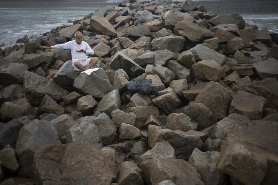 In this March 25, 2020 photo, Tomas Cabrera, 86, meditates on a jetty along the Pacific coast in Lima, Peru, defying a stay-at-home order decreed by the government to help reduce the spread of the novel coronavirus. Cabrera claimed it was a marvelous day for him because, "there were no people in the streets, no cars circulating, no factories running." (AP Photo/Rodrigo Abd)