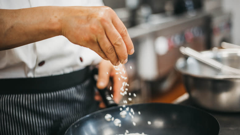 Chef adding salt to food