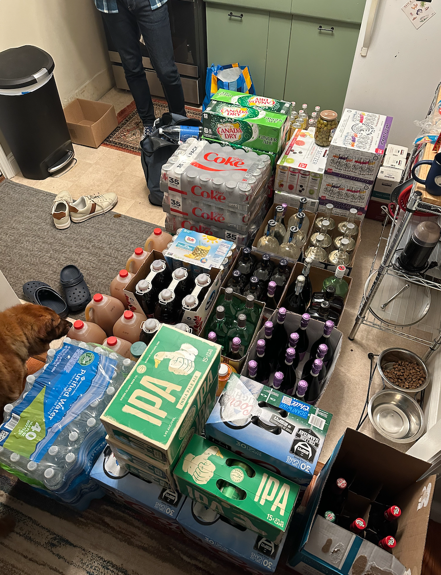 Author's small kitchen that's almost entirely covered with sodas, beer, wine, and other beverages in cases for his wedding