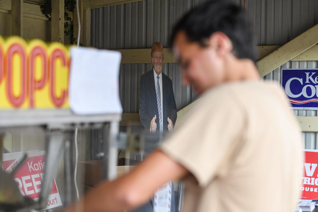 Surrounded by Ohio Republican campaign signs and a cardboard cutout of Republican presidential nominee Donald Trump, Max Graham mans the Summit County Republican Party's table at the Summit County Fair July 25 in Tallmadge.