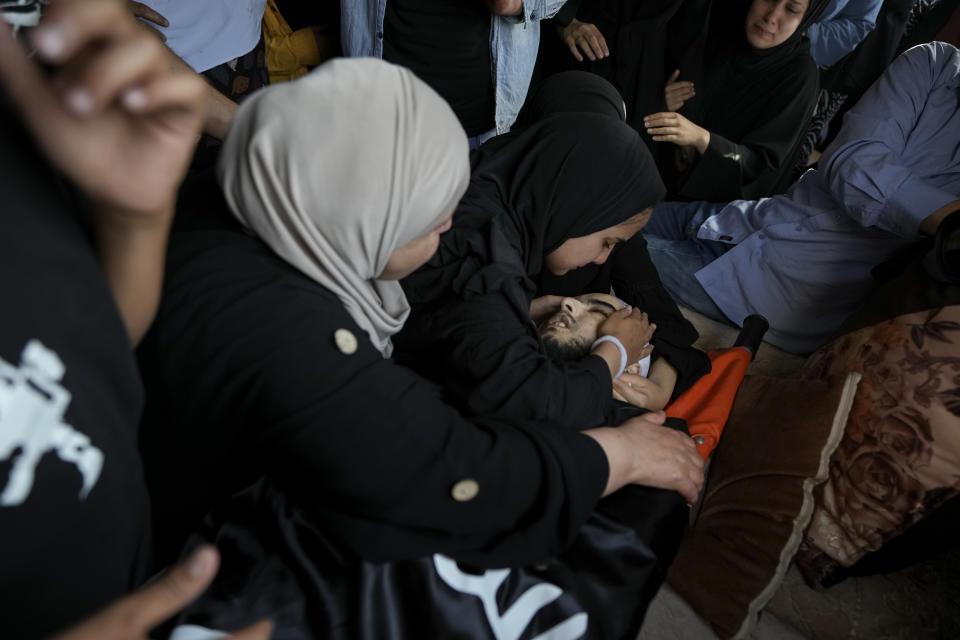 Mourners gather around the body of Palestinian Bara Lahlouh, 24, during his funeral at his family home, in the West Bank town of Jenin, Friday, June 17, 2022. Israeli forces shot dead Lahlouh and another two Palestinians and wounded eight others early Friday during a military operation in the occupied West Bank town of Jenin, the Palestinian Health Ministry said. The military said the troops traded fire with militants. (AP Photo/Nasser Nasser)