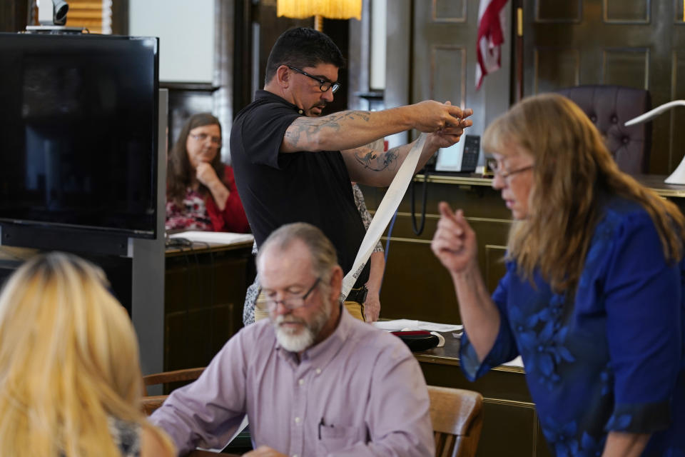 Esmeralda County Commissioner Tim Hipp, top center, rolls up printed voting results during a hand recount of votes, Friday, June 24, 2022, in Goldfield, Nev. Commissioners in tiny Esmeralda County on Friday afternoon began hand-counting all ballots after residents raised concerns at their certification meeting on Thursday. (AP Photo/John Locher)