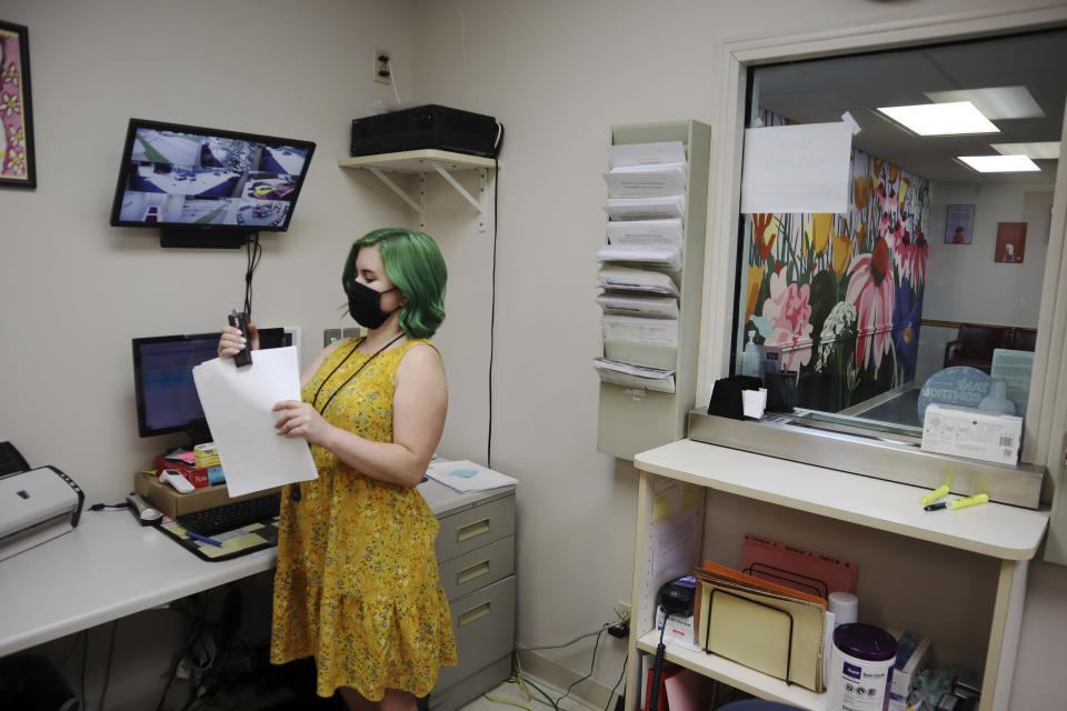 Beth Fiddler, a receptionist and telephone counselor at the Women's Health Center of West Virginia, staples paperwork in her office outside the clinic's empty waiting room on Wednesday, June 29, 2022 in Charleston, W.Va. (AP Photo/Leah Willingham)