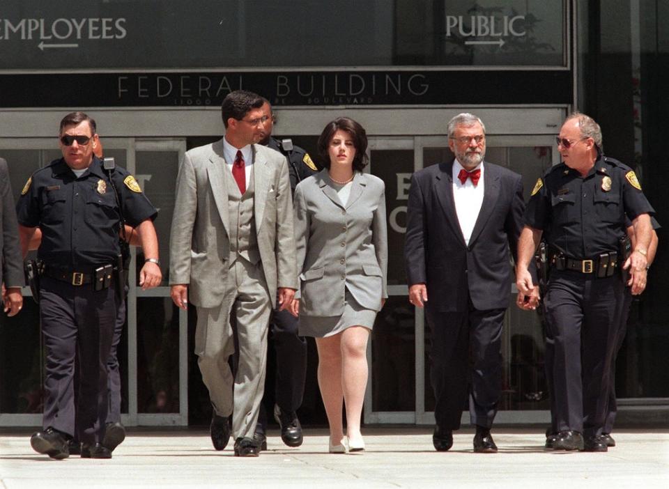 Monica Lewinsky (center) is escorted by police officers, federal Investigators, and her attorney William Ginsburg as she leaves the Federal Building on 28 May 1998 in Westwood, California, after submitting new evidence to Ken Starr’s office (VINCE BUCCI/AFP via Getty Images)