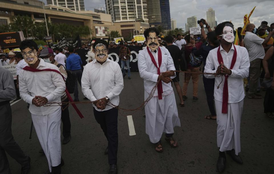 FILE - Sri Lankan protesters wear masks of president Gotabaya Rajapaksa's family members during a march demanding Gotabaya resign, at the ongoing protest site in Colombo, Sri Lanka, April 29, 2022. With one brother president, another prime minister and three more family members cabinet ministers, it appeared that the Rajapaksa clan had consolidated its grip on power in Sri Lanka after decades in and out of government. With a national debt crisis spiraling out of control, it looks like the dynasty is nearing its end with Prime Minister Mahinda stepping down on Monday, May 9, 2022, and the three Rajapaksas resigning their cabinet posts in April, but the family is not going down without a fight. (AP Photo/Eranga Jayawardena, File)