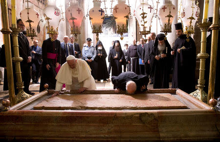 FILE PHOTO: Pope Francis (L) and Constantinople Patriarch Bartholomew kneel to kiss the Stone of Unction, traditionally claimed as the stone where Jesus' body was prepared for burial, in the Church of the Holy Sepulchre, in Jerusalem May 25, 2014. REUTERS/Andrew Medichini/Pool/File Photo