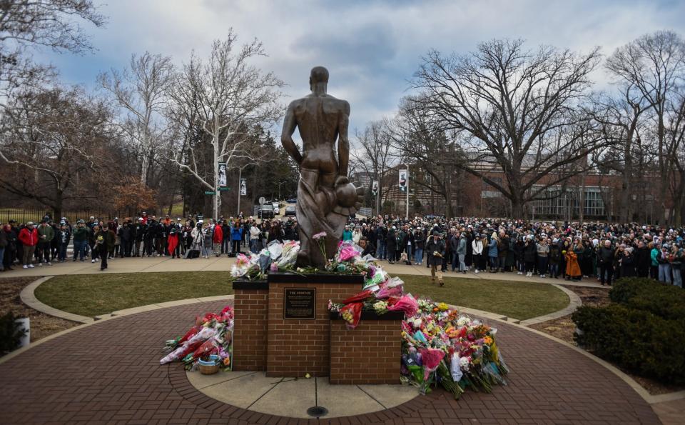 The Michigan State University community gathers by the Spartan statue on Feb. 15, before they walked along the Red Cedar River to the Rock for a vigil honoring the lives of three students killed during a shooting rampage on Feb. 13.
