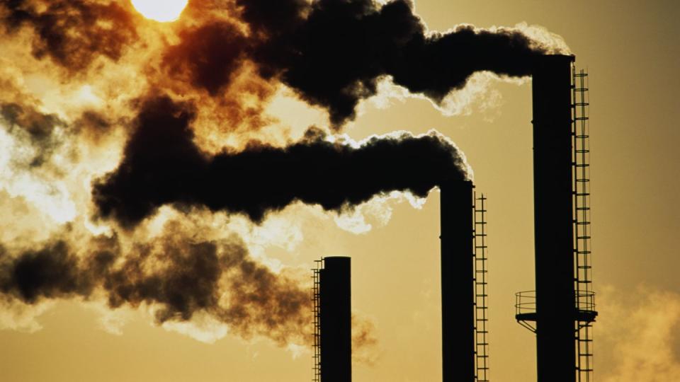 trio of industrial chimneys emitting smoke,sunset,silhouette