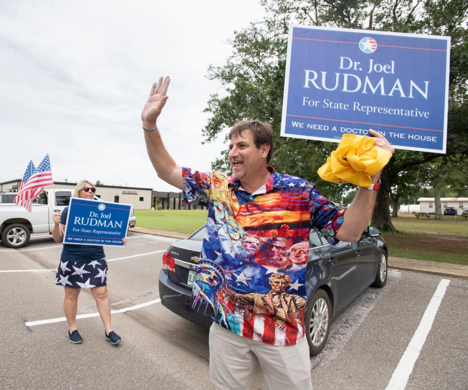 Dr. Joel Rudman, candidate for Florida House District 3, right, and his wife Sophie wave to passing vehicles outside the Santa Rosa County Auditorium on Primary Election Day in Milton on Tuesday, Aug. 23, 2022.