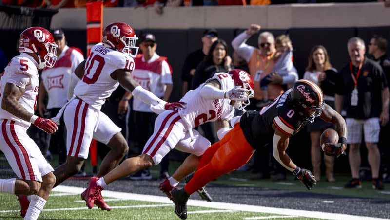 Oklahoma State running back Ollie Gordon II (0) dives for a touchdown in front of Oklahoma defensive back Billy Bowman Jr. (2), linebacker Kip Lewis (10), and defensive back Woodi Washington (5) in the first half of an NCAA college football game on Saturday, Nov. 4, 2023, in Stillwater, Okla.