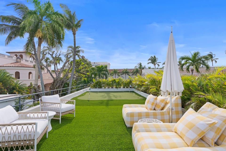 The rooftop deck is set up as a putting green with a seating area at one end.