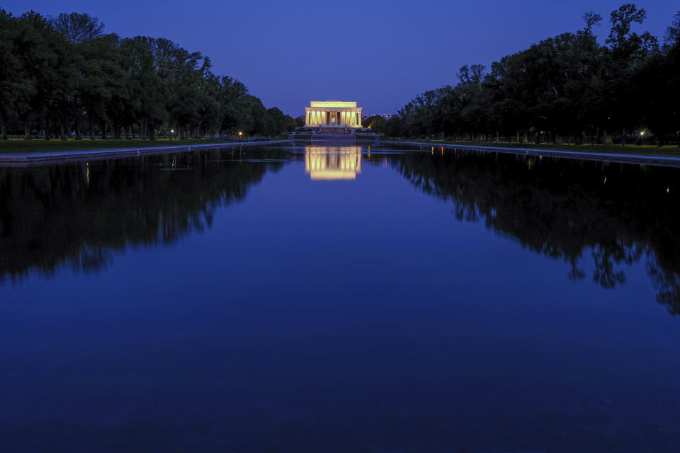 The Lincoln Memorial is reflected in the still waters of the reflecting pool on the National Mall in Washington before dawn, Wednesday, April 29, 2020. (AP Photo/J. David Ake)
