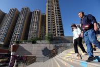 People walk past residential buildings next to the Evergrande City Plaza in Beijing